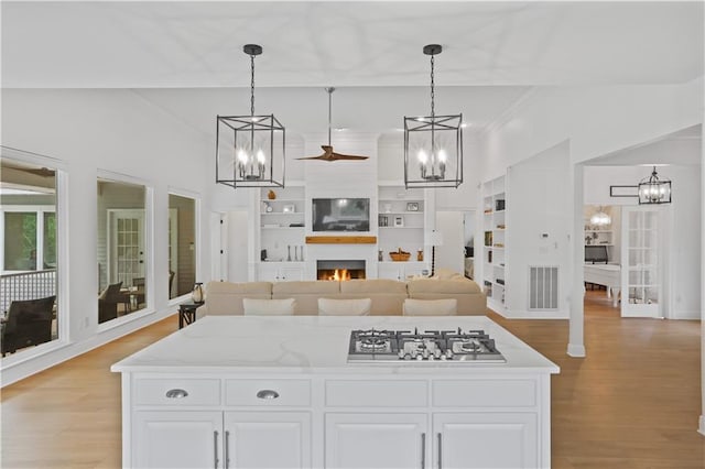 kitchen featuring a large fireplace, light wood-type flooring, visible vents, and white cabinetry