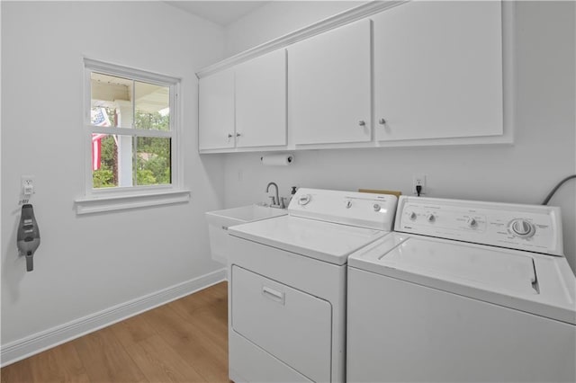 laundry area featuring light wood-style floors, washing machine and dryer, cabinet space, and baseboards