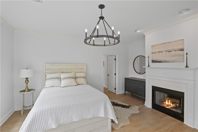 bedroom featuring crown molding, a premium fireplace, baseboards, and wood finished floors