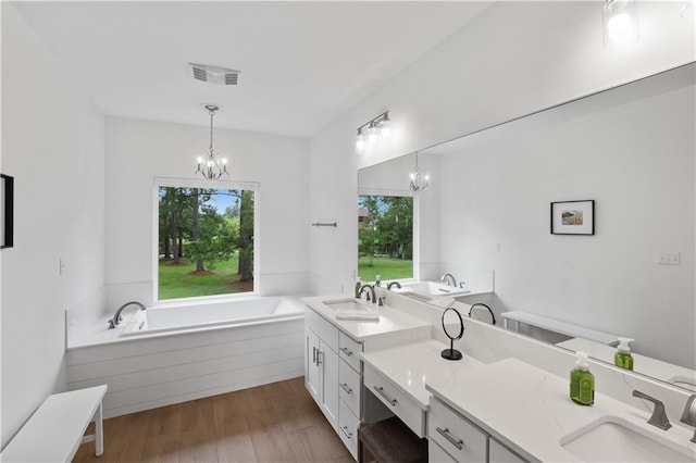 bathroom featuring wood finished floors, a sink, visible vents, and a notable chandelier