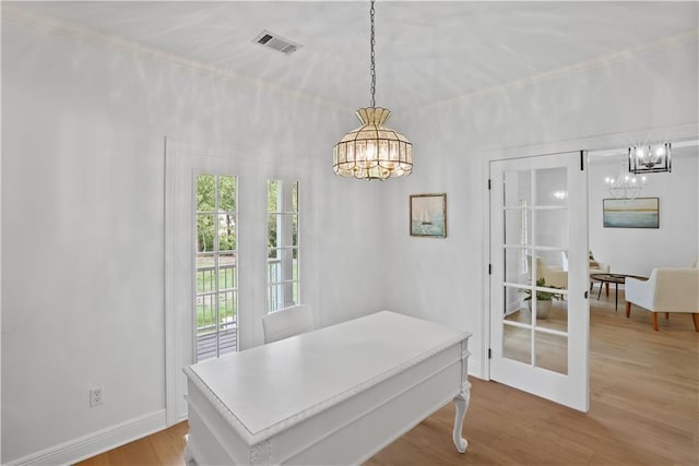 dining space with french doors, visible vents, a notable chandelier, and wood finished floors