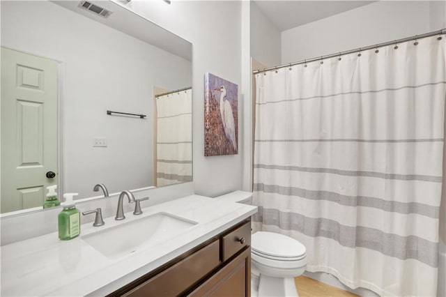 bathroom with toilet, vanity, and visible vents