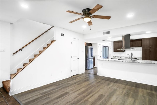 kitchen with dark wood-style floors, visible vents, freestanding refrigerator, dark brown cabinets, and island range hood