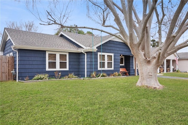 ranch-style home featuring a shingled roof and a front lawn