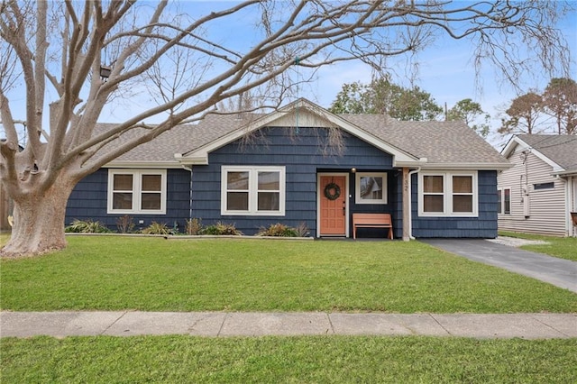 view of front of house with a shingled roof, a front yard, and driveway