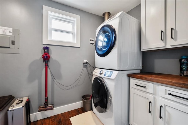 washroom with stacked washer / dryer, wood finished floors, baseboards, cabinet space, and radiator