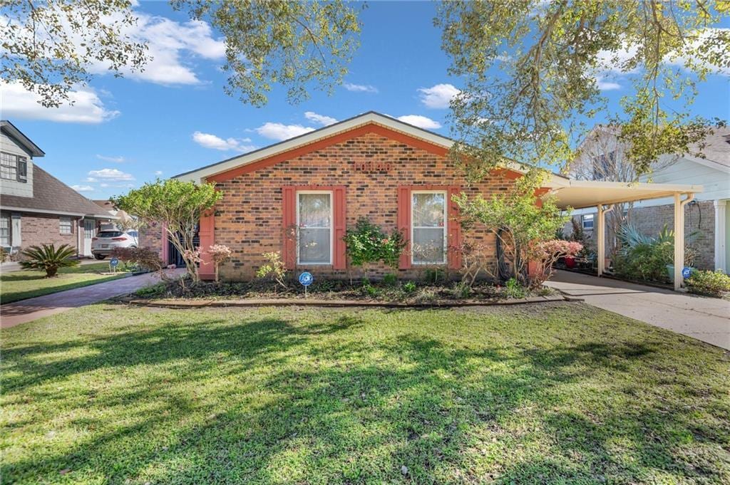 ranch-style house with a front yard, concrete driveway, brick siding, and an attached carport