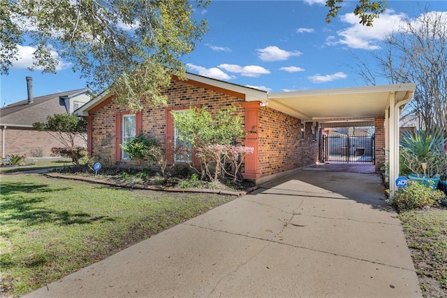 view of front of property featuring an attached carport, concrete driveway, brick siding, and a front lawn