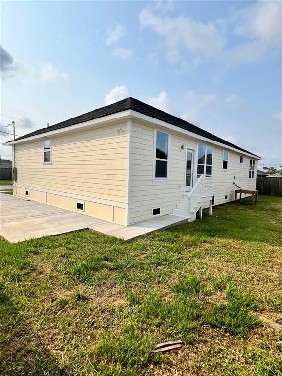 rear view of house featuring entry steps, a patio, crawl space, and a lawn