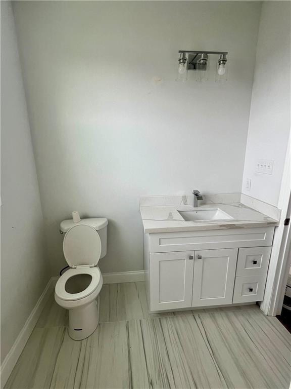 bathroom featuring baseboards, vanity, and toilet