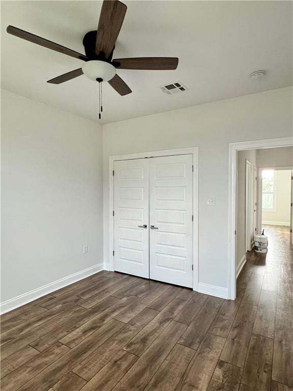 unfurnished bedroom featuring a closet, visible vents, dark wood finished floors, and baseboards