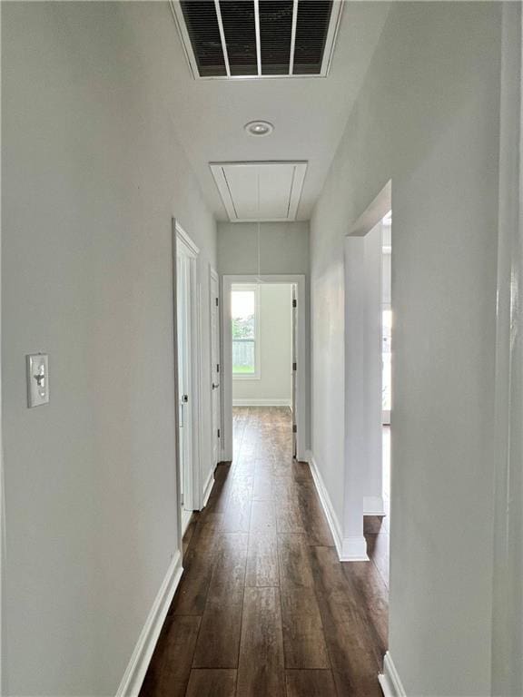 corridor with attic access, dark wood-style flooring, visible vents, and baseboards