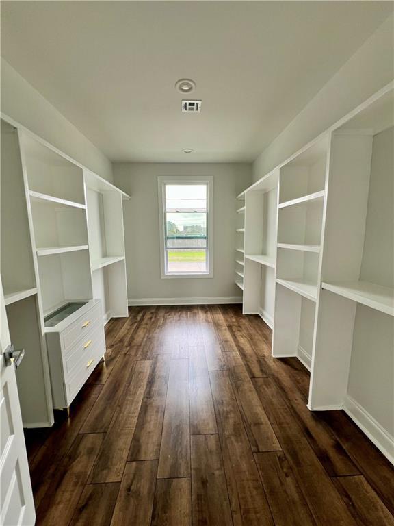 spacious closet with dark wood-type flooring and visible vents