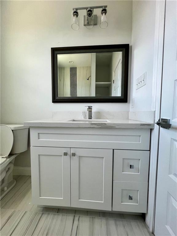 bathroom featuring vanity, toilet, and baseboards