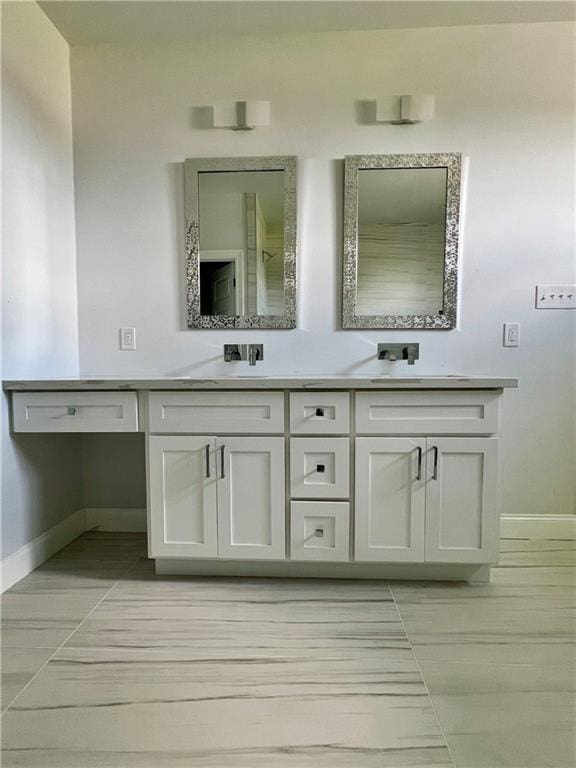 full bathroom featuring baseboards and double vanity