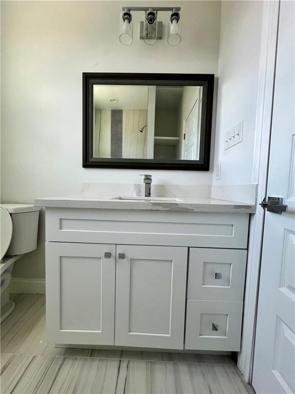 bathroom with vanity, toilet, and baseboards