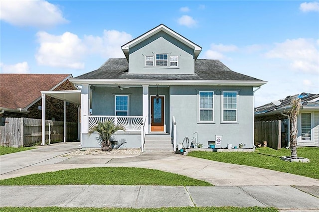 bungalow-style house with driveway, an attached carport, covered porch, a front lawn, and stucco siding