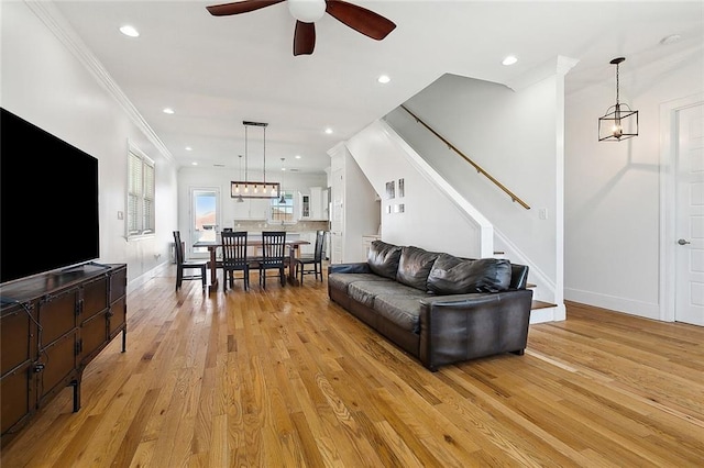 living area with crown molding, recessed lighting, stairway, light wood-type flooring, and baseboards