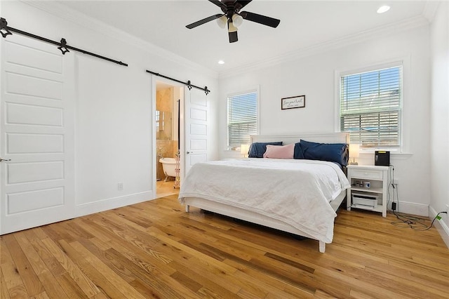 bedroom featuring multiple windows, crown molding, light wood finished floors, and a barn door