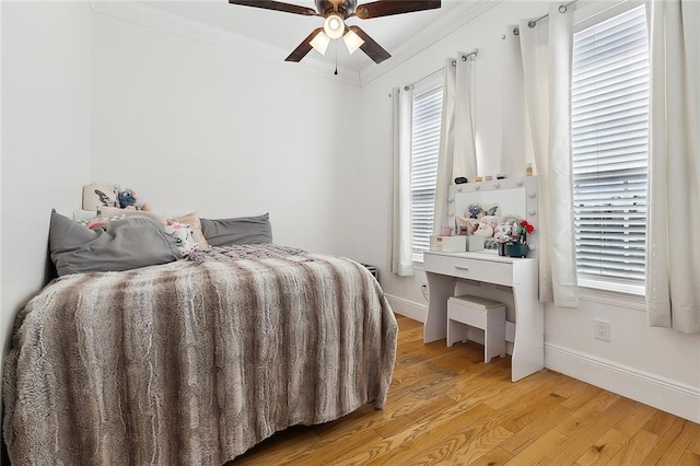 bedroom featuring multiple windows, crown molding, and light wood finished floors