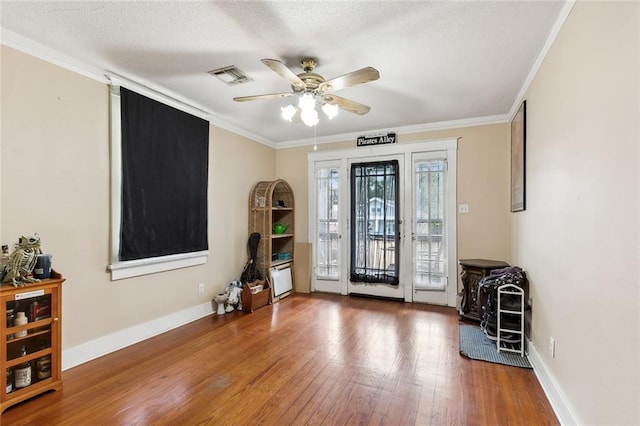 entrance foyer with baseboards, visible vents, hardwood / wood-style floors, and ornamental molding