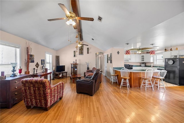 living area with arched walkways, vaulted ceiling with beams, visible vents, light wood-style flooring, and ceiling fan