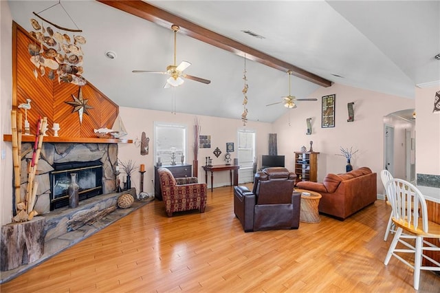 living room featuring arched walkways, vaulted ceiling with beams, a fireplace, visible vents, and wood finished floors