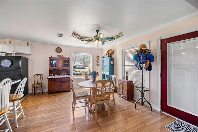 dining space with visible vents, baseboards, light wood-style flooring, ceiling fan, and ornamental molding