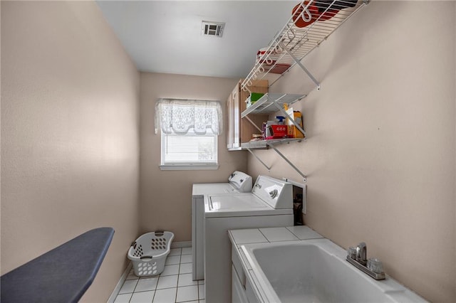 washroom with light tile patterned floors, baseboards, visible vents, washer and clothes dryer, and a sink