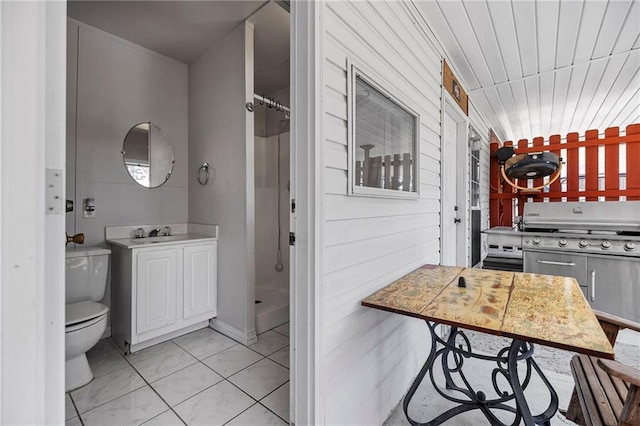 full bath with a stall shower, wooden walls, toilet, tile patterned flooring, and vanity