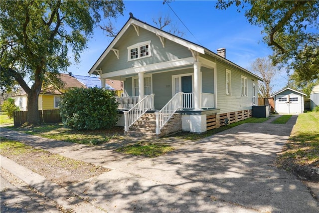 view of front facade with driveway, a garage, a chimney, an outdoor structure, and a porch