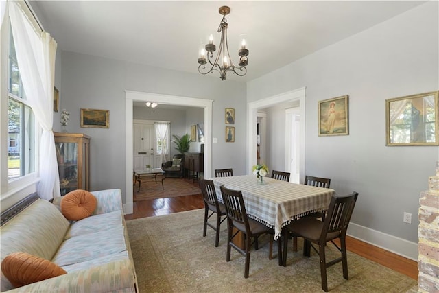 dining room with a notable chandelier, baseboards, and wood finished floors