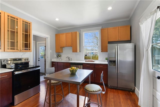 kitchen with stainless steel appliances, dark wood-style flooring, light countertops, and ornamental molding