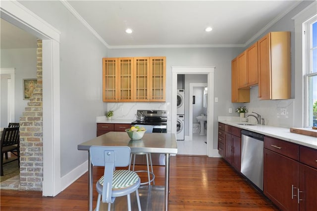 kitchen with a sink, appliances with stainless steel finishes, stacked washer / dryer, and dark wood finished floors