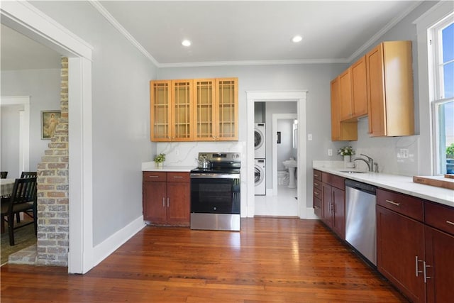 kitchen featuring stacked washer and dryer, light countertops, appliances with stainless steel finishes, decorative backsplash, and dark wood-style floors