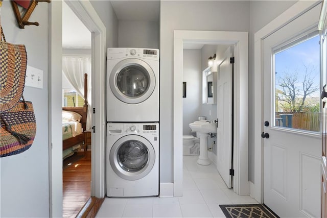 clothes washing area with stacked washer and clothes dryer, light tile patterned flooring, and laundry area