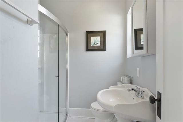 bathroom with baseboards, a sink, a shower stall, and toilet