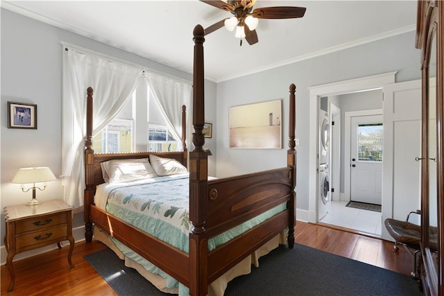 bedroom with crown molding, stacked washer / dryer, and wood finished floors