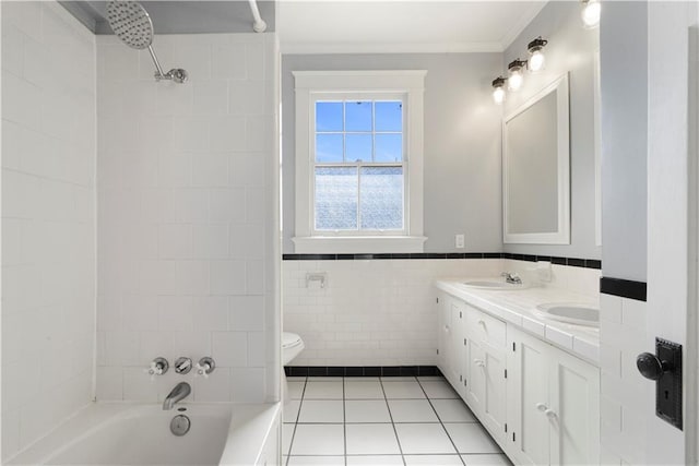 bathroom featuring toilet, a sink, tile walls, tile patterned floors, and double vanity