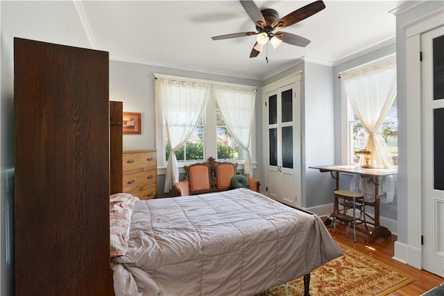 bedroom featuring ceiling fan, baseboards, crown molding, and wood finished floors