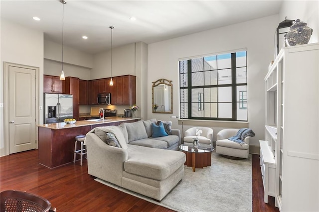 living area featuring a towering ceiling, dark wood-style flooring, and recessed lighting