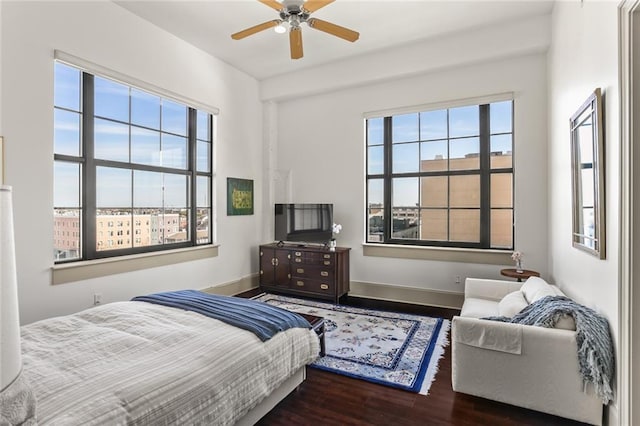 bedroom featuring multiple windows, baseboards, and wood finished floors