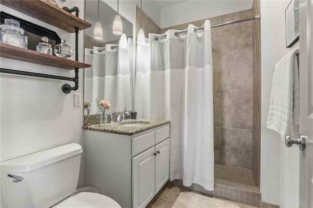 full bathroom featuring tiled shower, vanity, and toilet