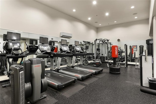 exercise room featuring a towering ceiling, recessed lighting, and a wall mounted air conditioner