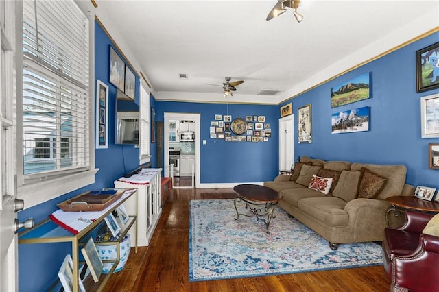 living room with ceiling fan, baseboards, and wood finished floors