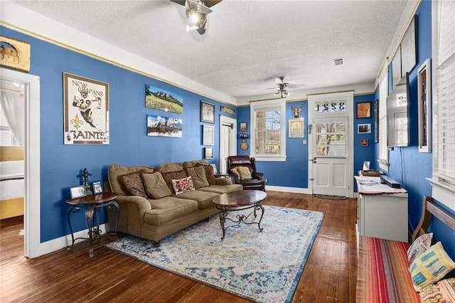 living area featuring ceiling fan, dark wood-type flooring, a textured ceiling, and visible vents