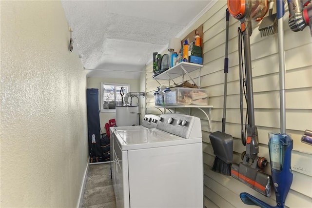 clothes washing area with a textured ceiling, a textured wall, baseboards, water heater, and independent washer and dryer