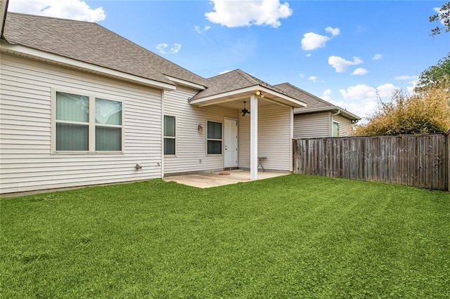 back of house with a yard, a patio, fence, and roof with shingles