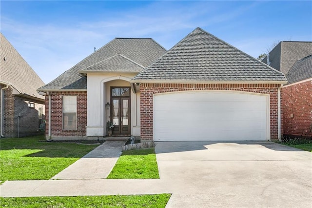 view of front of house featuring a garage, brick siding, concrete driveway, french doors, and roof with shingles