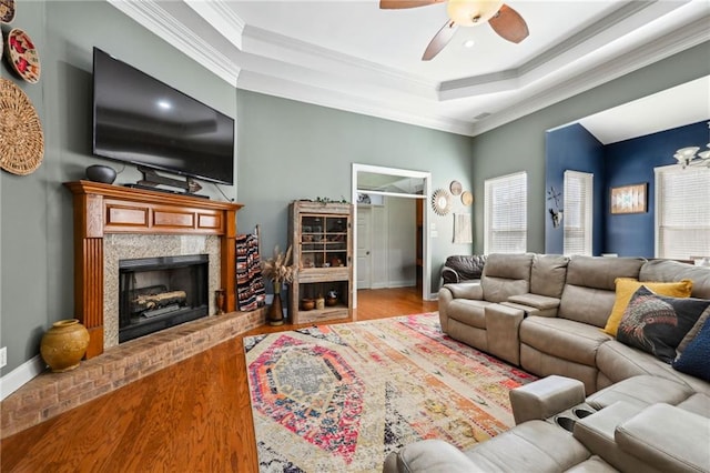 living room with a raised ceiling, crown molding, and wood finished floors